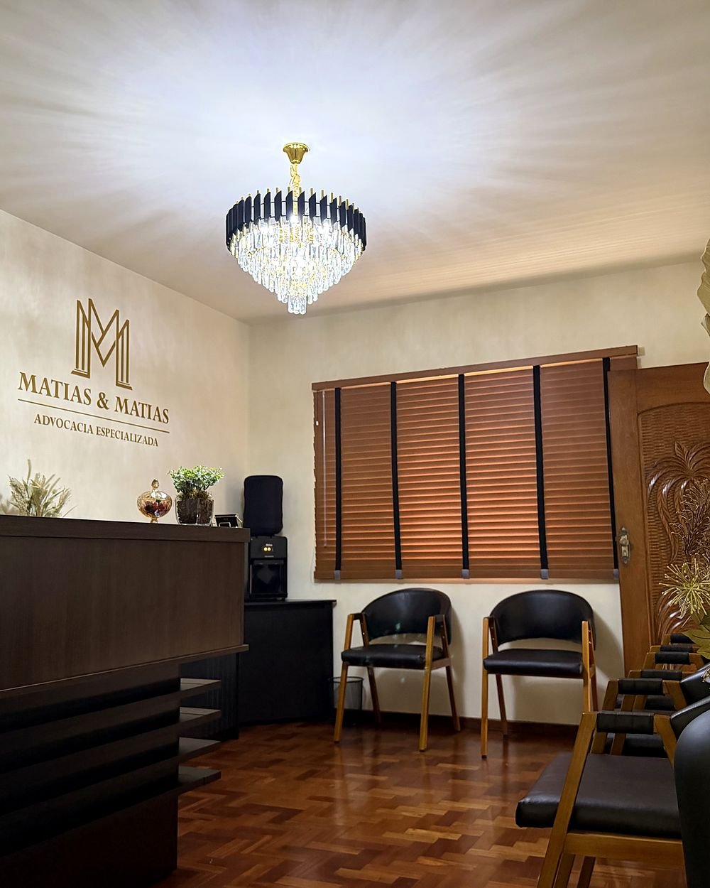 Sala de espera com poltronas, balcão de recepção e lustre de cristal